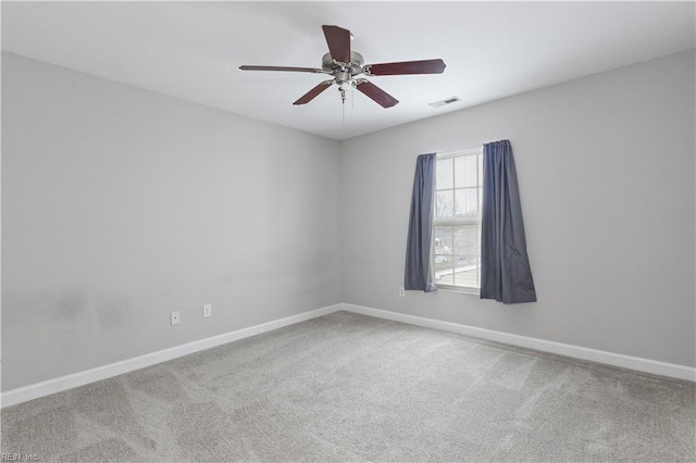 carpeted spare room with visible vents, baseboards, and a ceiling fan