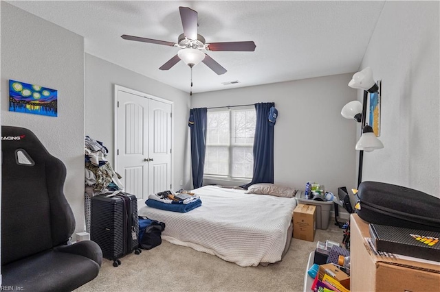 carpeted bedroom with a closet, visible vents, and ceiling fan