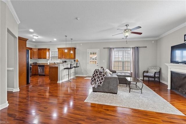 living room featuring dark wood finished floors, baseboards, crown molding, and a ceiling fan