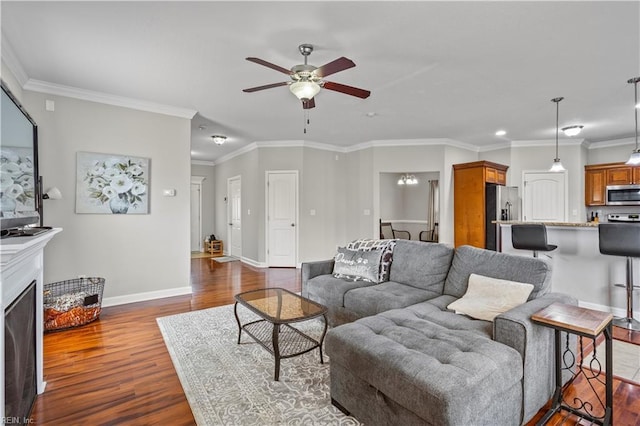 living room with dark wood-style floors, baseboards, ceiling fan, and ornamental molding