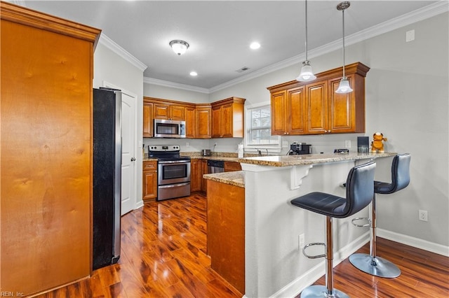 kitchen featuring brown cabinets, ornamental molding, dark wood finished floors, stainless steel appliances, and a peninsula