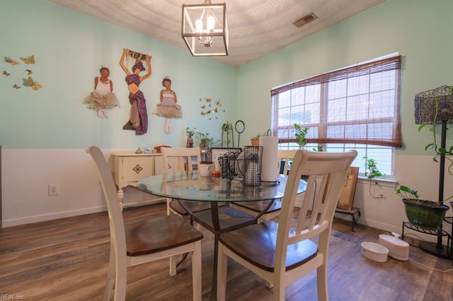 dining area with a notable chandelier, visible vents, baseboards, and wood finished floors