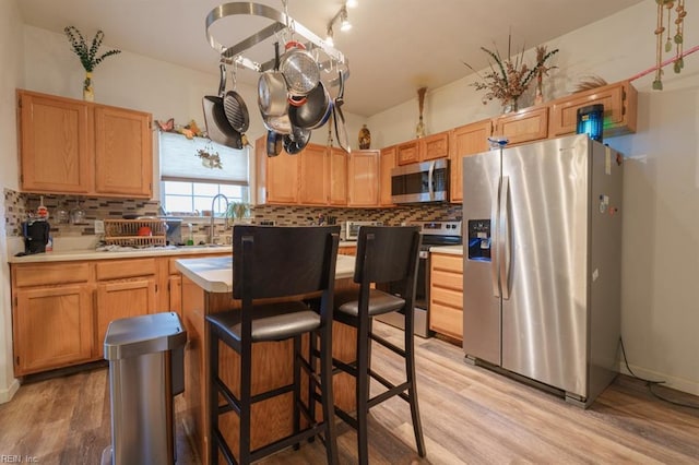 kitchen with light wood-style floors, stainless steel appliances, backsplash, and light countertops