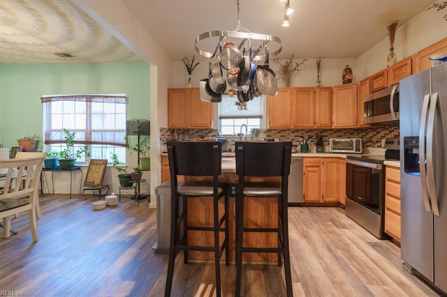 kitchen featuring tasteful backsplash, a toaster, stainless steel appliances, and light wood-type flooring