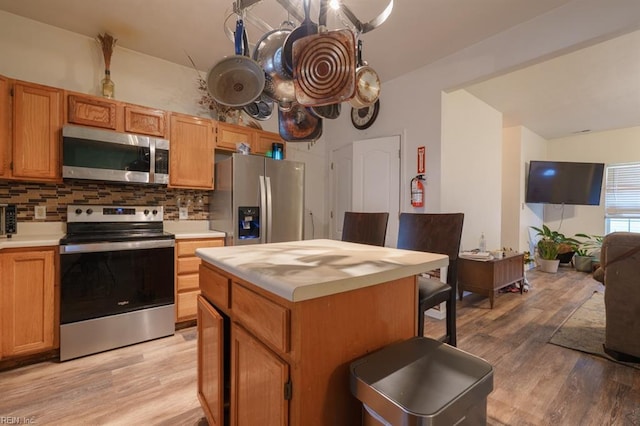 kitchen with decorative backsplash, light countertops, light wood-type flooring, and stainless steel appliances