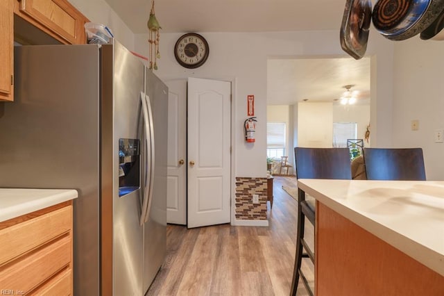 kitchen featuring light countertops, light wood-style flooring, a breakfast bar area, and stainless steel fridge