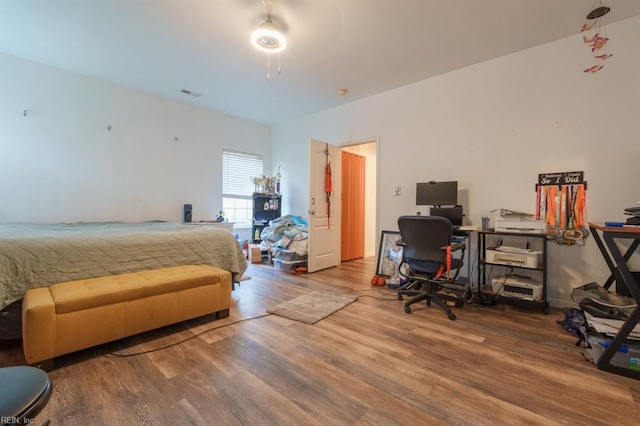 bedroom with ceiling fan, visible vents, and wood finished floors