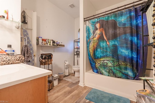 bathroom featuring vanity, wood finished floors, visible vents, shower / bath combo, and toilet