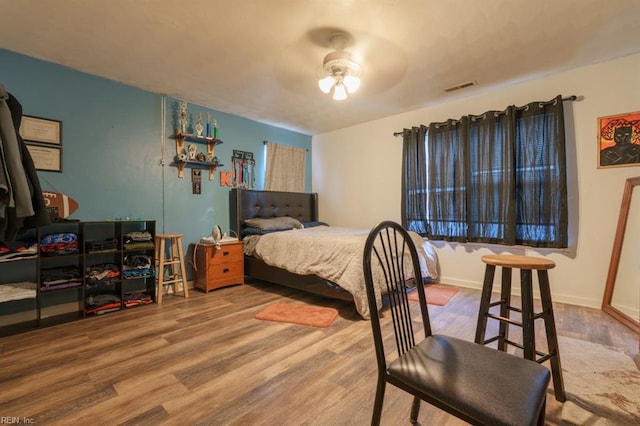 bedroom with visible vents, baseboards, and wood finished floors