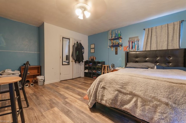 bedroom with wood finished floors, a closet, and baseboards