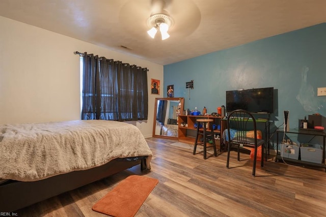 bedroom with visible vents, baseboards, and wood finished floors