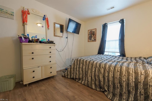 bedroom featuring visible vents, baseboards, and wood finished floors