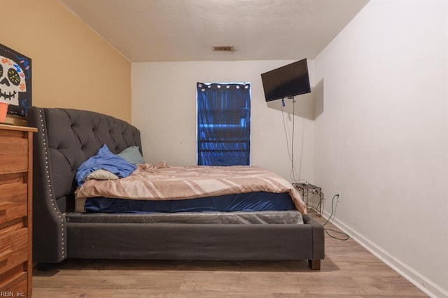 bedroom with visible vents, wood finished floors, and baseboards