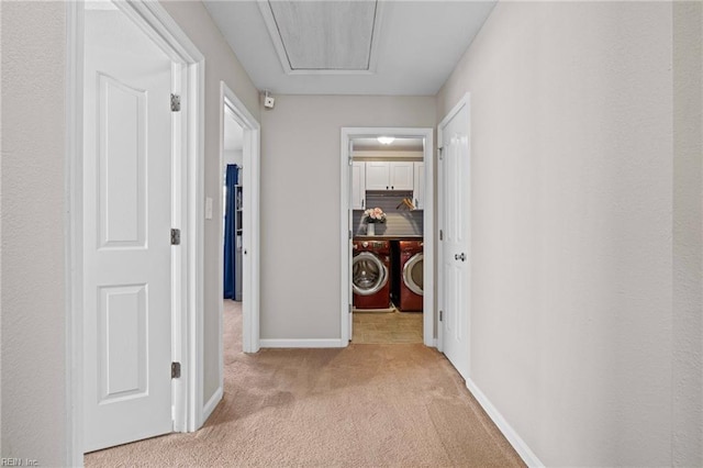 hall featuring attic access, carpet flooring, baseboards, and independent washer and dryer