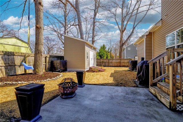 view of yard with a patio, an outbuilding, a fenced backyard, and an outdoor fire pit