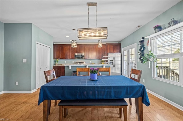 dining space featuring visible vents, baseboards, and light wood finished floors