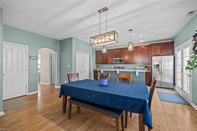 dining area featuring visible vents, recessed lighting, arched walkways, light wood finished floors, and baseboards