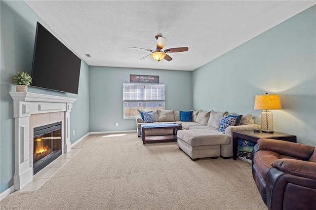 carpeted living room featuring baseboards, a textured ceiling, ceiling fan, and a tiled fireplace