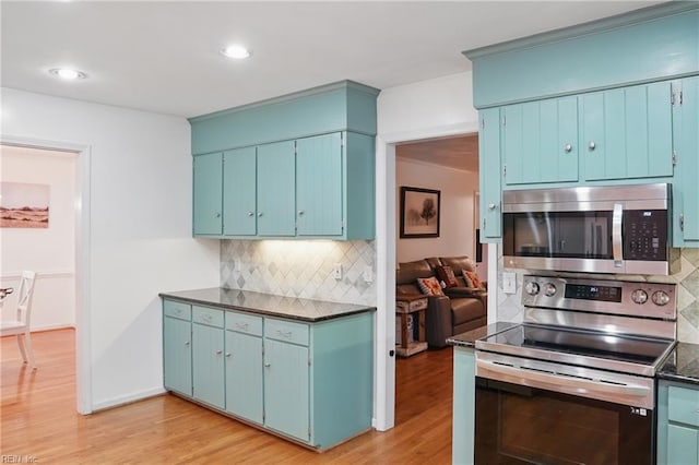 kitchen featuring dark countertops, stainless steel appliances, light wood-style floors, and tasteful backsplash