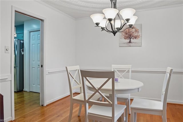 dining space with an inviting chandelier, light wood-style flooring, and ornamental molding