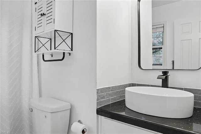 full bathroom featuring toilet, tasteful backsplash, and a sink