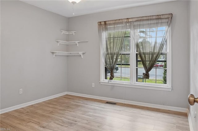 empty room with visible vents, baseboards, and wood finished floors