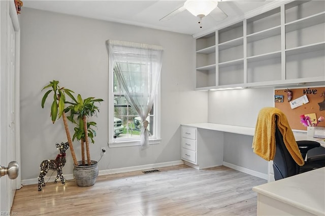 office area featuring baseboards, built in study area, a ceiling fan, and light wood finished floors