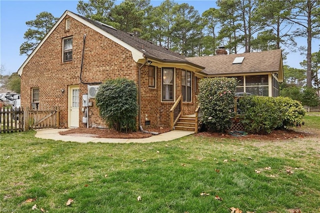 rear view of property featuring brick siding, fence, a lawn, a chimney, and a sunroom