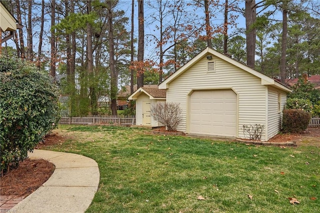 view of yard featuring a garage, an outbuilding, and fence