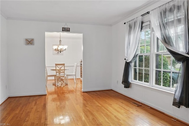 spare room featuring visible vents, baseboards, a notable chandelier, and light wood finished floors