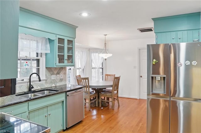 kitchen with tasteful backsplash, visible vents, light wood finished floors, stainless steel appliances, and a sink