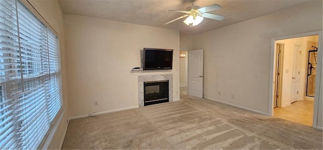 unfurnished living room featuring a glass covered fireplace, carpet, baseboards, and ceiling fan