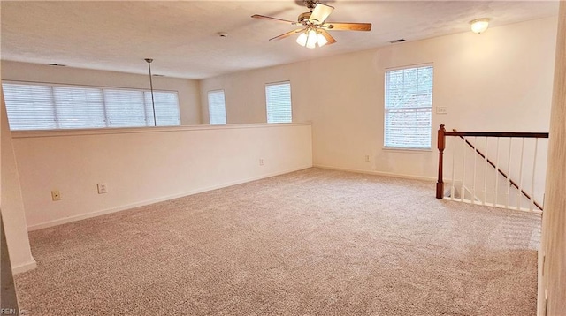 carpeted empty room featuring visible vents, baseboards, and a ceiling fan