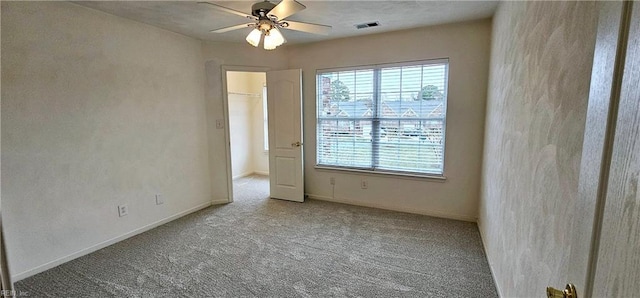 carpeted empty room featuring visible vents, baseboards, and a ceiling fan