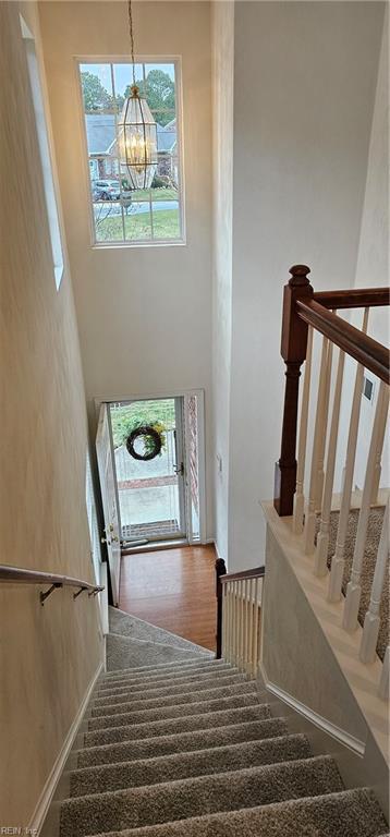 stairway with a towering ceiling and a chandelier