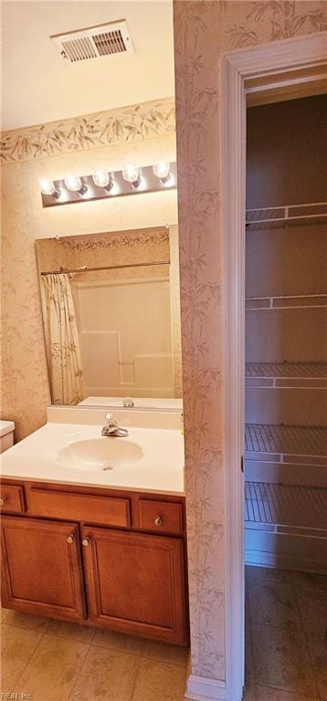 bathroom with visible vents, vanity, and wallpapered walls