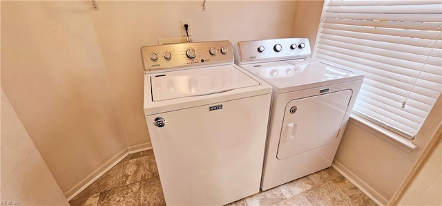 clothes washing area with laundry area, washing machine and dryer, and baseboards