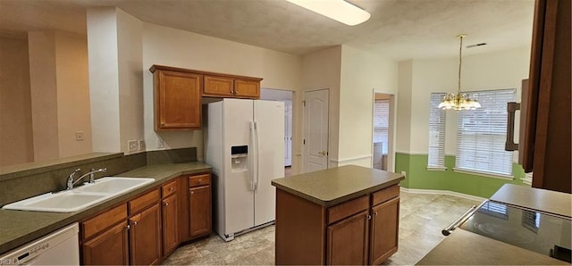 kitchen featuring visible vents, brown cabinets, a notable chandelier, white appliances, and a sink