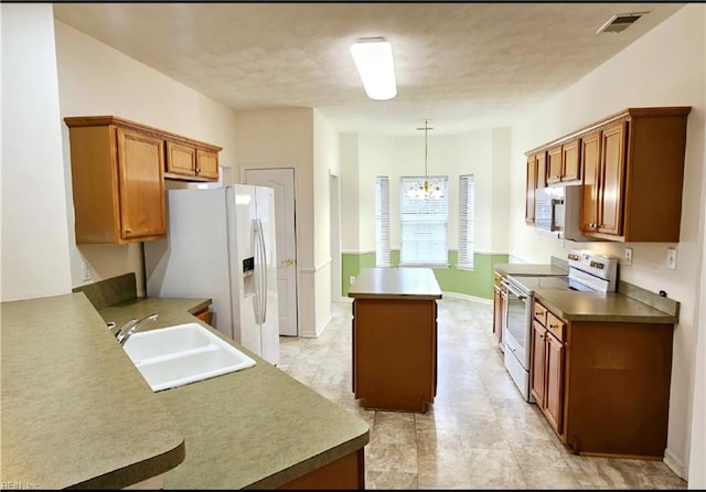 kitchen featuring a sink, electric stove, white refrigerator with ice dispenser, stainless steel microwave, and a chandelier