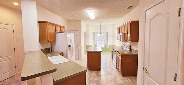 kitchen featuring a sink, visible vents, white appliances, and brown cabinets