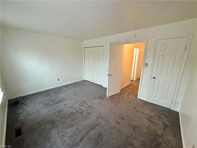 unfurnished bedroom with a closet, baseboards, visible vents, and dark carpet