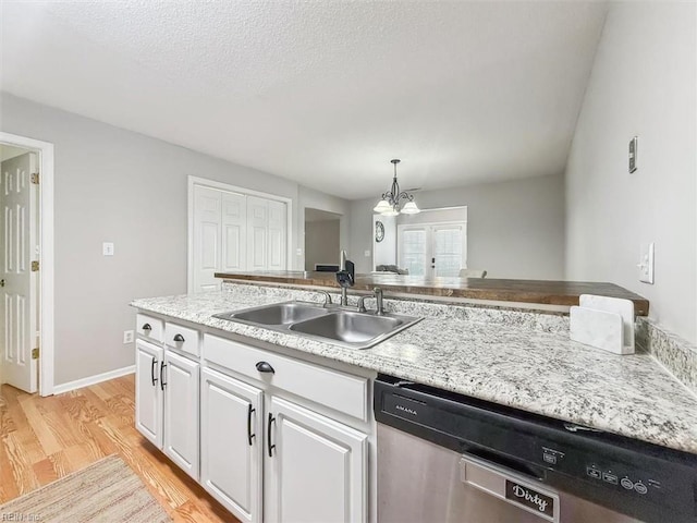 kitchen with a sink, white cabinets, light wood-style floors, a textured ceiling, and dishwasher