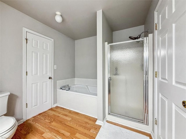 bathroom featuring toilet, wood finished floors, a shower stall, and a bath