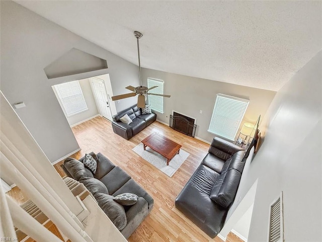 living room with visible vents, a textured ceiling, wood finished floors, and vaulted ceiling