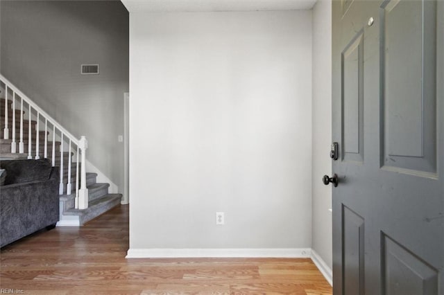 foyer entrance with visible vents, light wood-style flooring, stairway, and baseboards