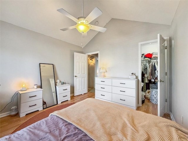 bedroom featuring light wood finished floors, a walk in closet, a closet, and vaulted ceiling