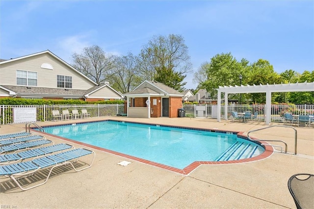 pool featuring a patio, fence, and an outbuilding