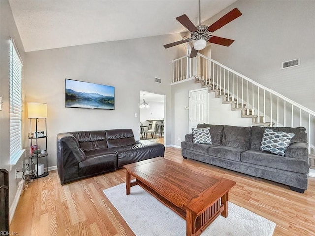 living room featuring visible vents, baseboards, stairs, ceiling fan with notable chandelier, and wood finished floors