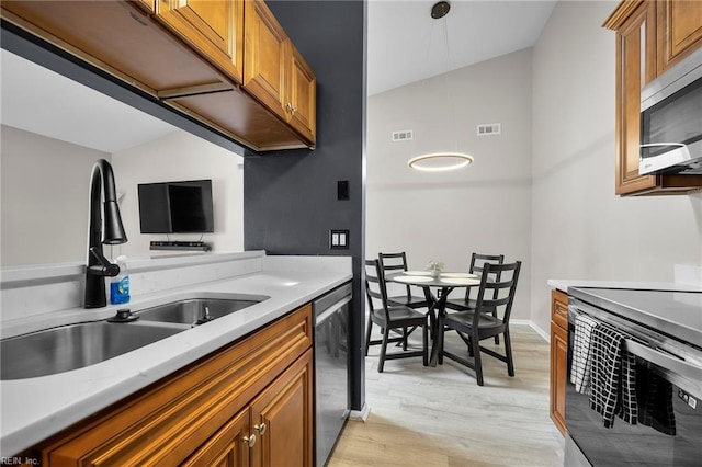 kitchen featuring visible vents, brown cabinets, light wood-style flooring, stainless steel appliances, and a sink