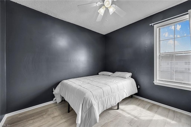 bedroom with wood finished floors, baseboards, a textured ceiling, and ceiling fan